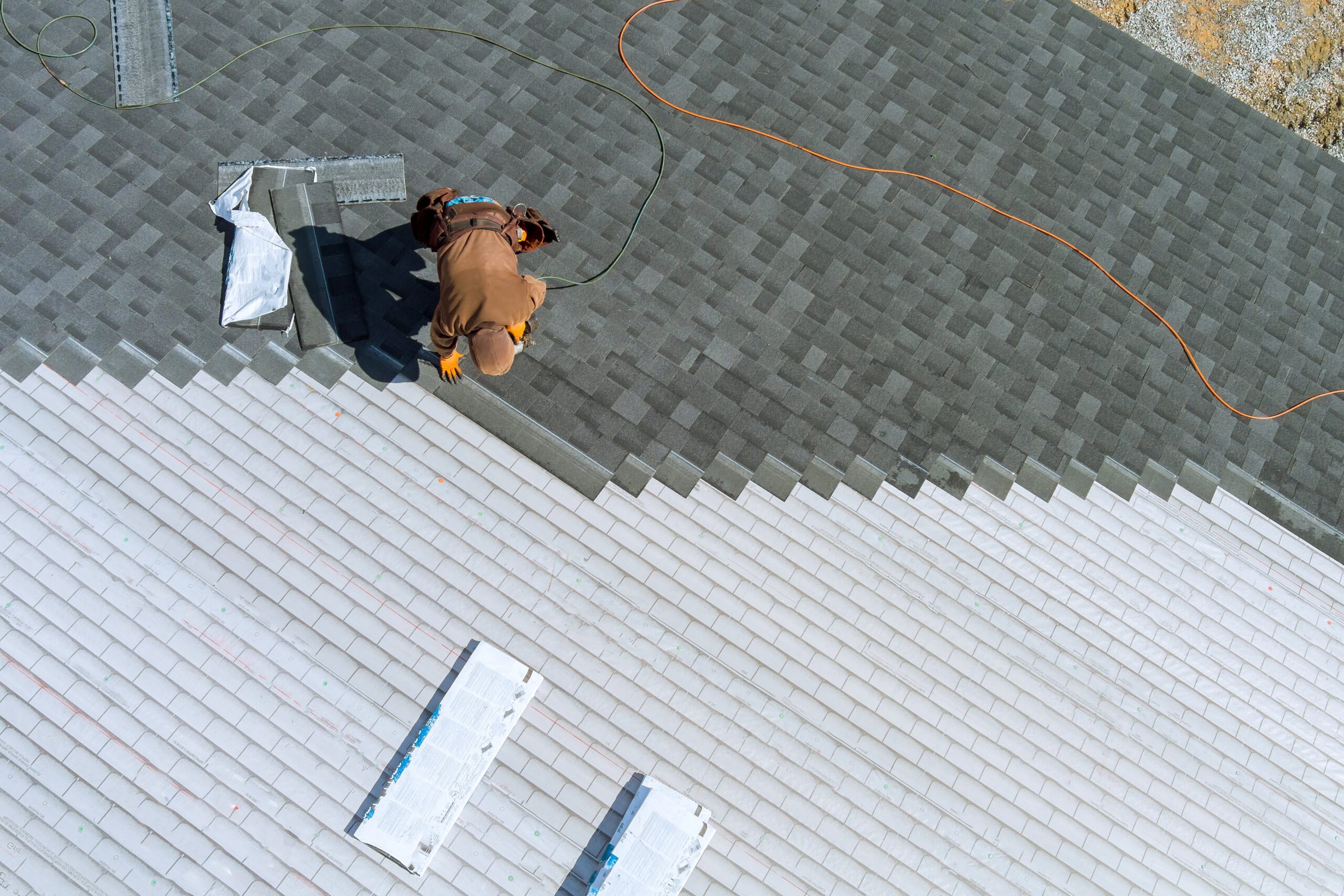 worker installing shingles roof home with air hammer nails scaled